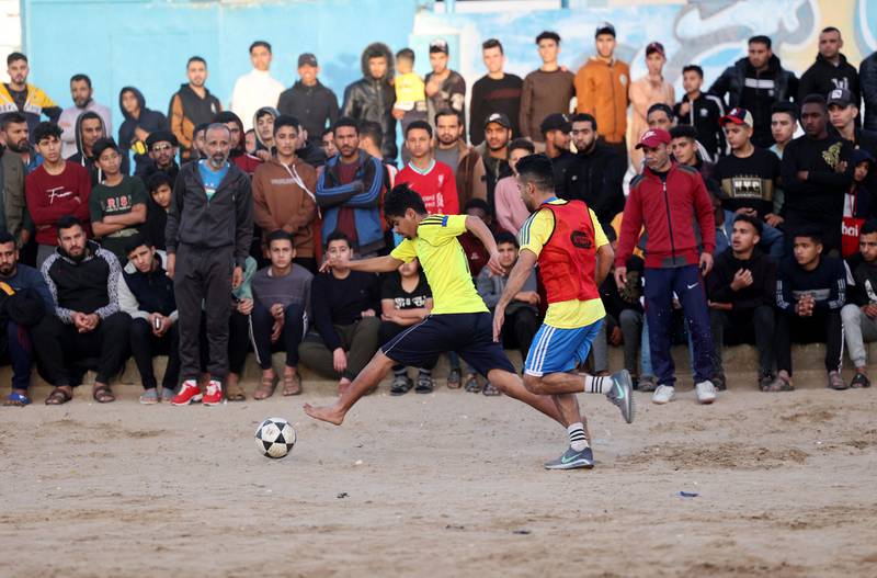 Palestinian youths play football at a refugee camp in Rafah, in the southern Gaza Strip, before breaking their fast during the Muslim holy month of Ramadan on April 11, 2022.  - Throughout the month, devout Muslims must abstain from food and drink from dawn until sunset when they break the fast with the Iftar meal.  (Photo by SAID KHATIB  /  AFP)