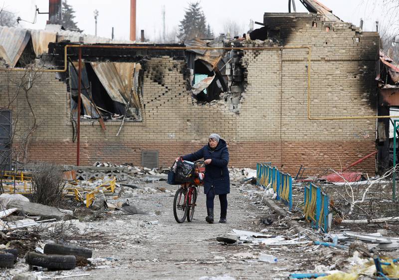 A woman walks with a bicycle next to a building damaged during the conflict in the separatist-controlled town of Volnovakha, Donetsk region. Reuters