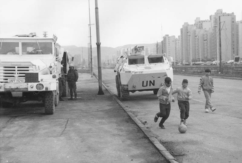 Children playing football beside UN vehicles parked in Sarajevo in September 1993. Getty Images