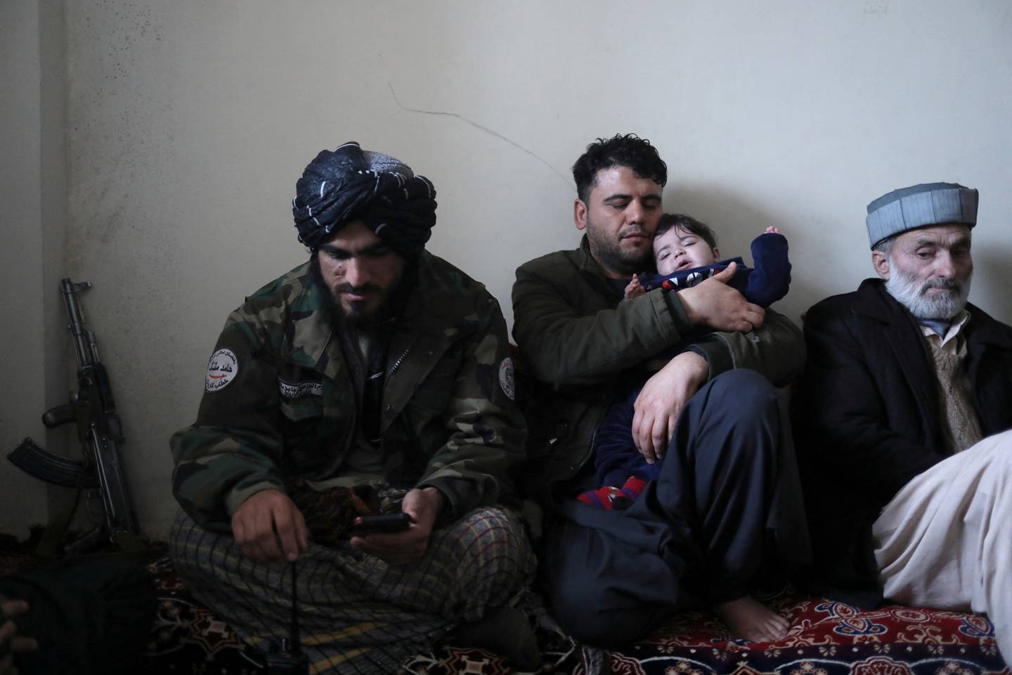 Hamid Safi, who found Sohail Ahmadi in the airport, holds the baby next to Sohail's grandfather Mohammad Qasem Razawi and a Taliban representative. Reuters