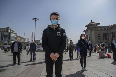 BEIJING, CHINA - APRIL 04: Chinese travellers wear protective masks as they bow their heads at 10 AM for three minutes of silence to mark the country's national day of mourning for COVID-19 at Beijing Railway Station on April 4, 2020 in Beijing, China. Across the country people paused, and sirens and horns wailed for three minutes to remember medical personnel and patients who died during the coronavirus outbreak. With the pandemic hitting hard across the world, officially the number of coronavirus cases in China is dwindling, since the government imposed sweeping measures to keep the disease from spreading.  For two months, millions of people across China have been restricted in how they move from their homes, while other cities have been locked down in ways that appeared severe at the time but are now being replicated in other countries trying to contain the virus. In Beijing, it is mandatory to wear masks outdoors, retail stores operate on reduced hours, restaurants employ social distancing among patrons, and tourist attractions at risk of drawing large crowds remain closed. Since January, China has recorded more than 81,000 cases of COVID-19 and at least 3200 deaths, mostly in and around the city of Wuhan, in central Hubei province, where the outbreak first started. (Photo by Kevin Frayer/Getty Images)