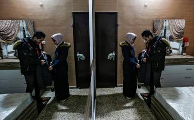 Palestinian groom Ahmed al-Ketnani, 27, stands before his 19-year-old fiancee Sara while holding his groom's suit, at their wedding room in his home in Gaza City, after having decided to postpone their nuptials due to the COVID-19 coronavirus disease pandemic.  AFP