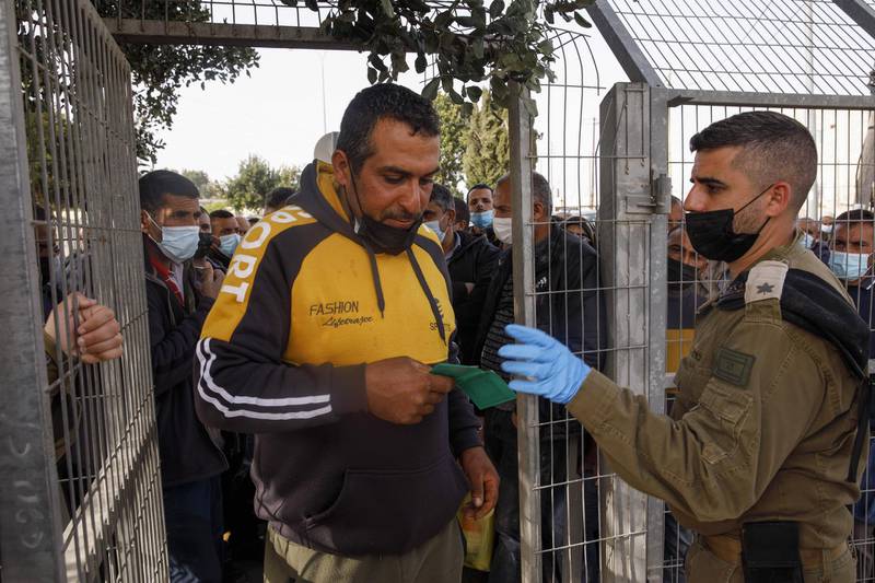 An Israeli soldier checks the documents of a Palestinian labourer at a temporary vaccination centre at the Rachel's Tomb checkpoint crossing into Israel, in Bethlehem, West Bank. Bloomberg