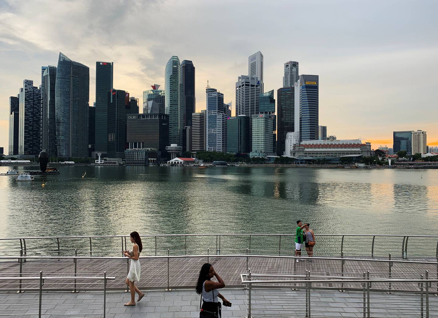 FILE PHOTO: Passers-by hold their mobile phones as people take a selfie photo using a smartphone, with Singapore's central business district skyline, in Singapore, May 10, 2019. REUTERS/Kevin Lam/File Photo    GLOBAL BUSINESS WEEK AHEAD