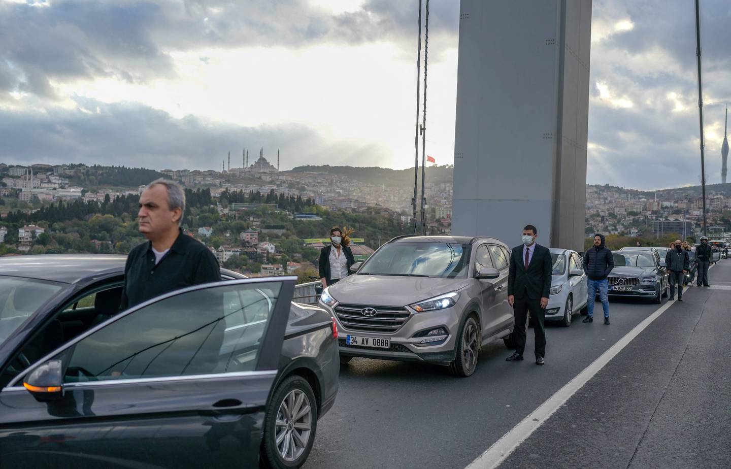 People stand by their vehicles to pay their respects at 09:05 am, the time of death of Mustafa Kemal Ataturk, founder of the Republic of Turkey, on November 10, 2021, in Istanbul, at the 15 July Martyrs Bridge. AFP
