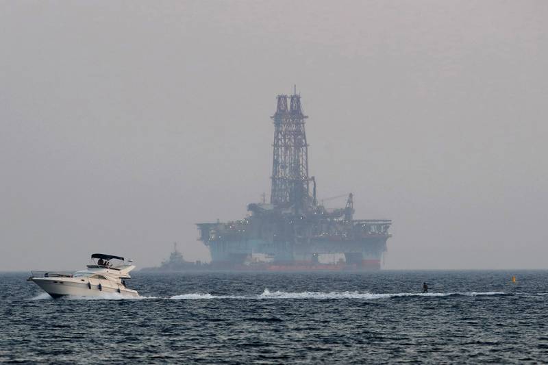 An offshore drilling rig is seen in the waters off Cyprus's coastal city of Limassol as a boat passes with a skier. AP Photo