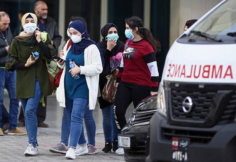 People wear face masks as they walk outside of the Rafik Hariri University Hospital where a woman is treated for coronavirus, the first case in Beirut, Lebanon.  EPA