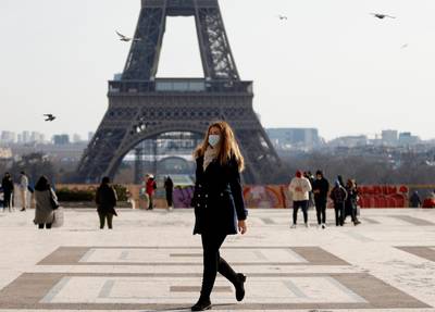 A woman, wearing protective face masks, walks in front of the Eiffel tower at the Trocadero in Paris amid the coronavirus disease (COVID-19) outbreak in France, February 11, 2021. REUTERS/Sarah Meyssonnier
