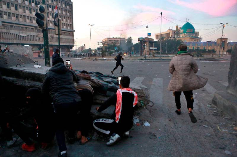 Anti-government protesters take cover during clashes with security forces in Khilani Square in Baghdad. AP Photo