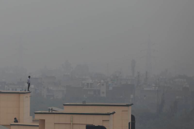 A man is seen standing on the ledge of a building as smog envelopes the horizon in New Delhi, India. AP Photo