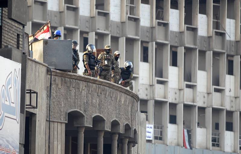 Iraqi security forces stand guard atop a building amid clashes with protesters at Baghdad's Khallani square during ongoing anti-government demonstrations. AFP