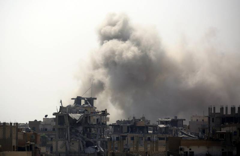 Smoke rises from building in Raqa's eastern al-Sanaa neighbourhood, on the edge of the old city, on August 13, 2017, as Syrian Democratic Forces (SDF), a US backed Kurdish-Arab alliance, battle to retake the city from the Islamic State (IS) group. (Photo by Delil souleiman / AFP)