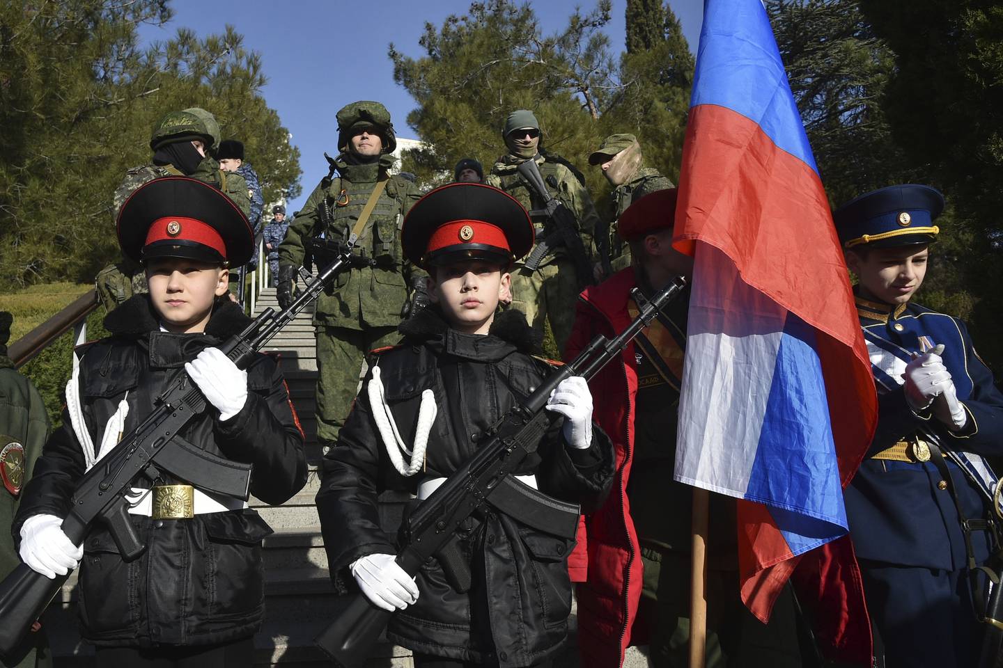 Schüler einer Militärschule und russische Soldaten auf der Krim stehen vor Tafeln mit den Namen russischer Truppen, die bei Kämpfen in der Ukraine gefallen sind.  AP