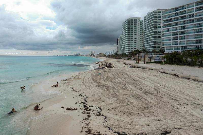 The beach is empty where a few tourists spend time on the waters' edge in Cancun, Mexico. AP Photo