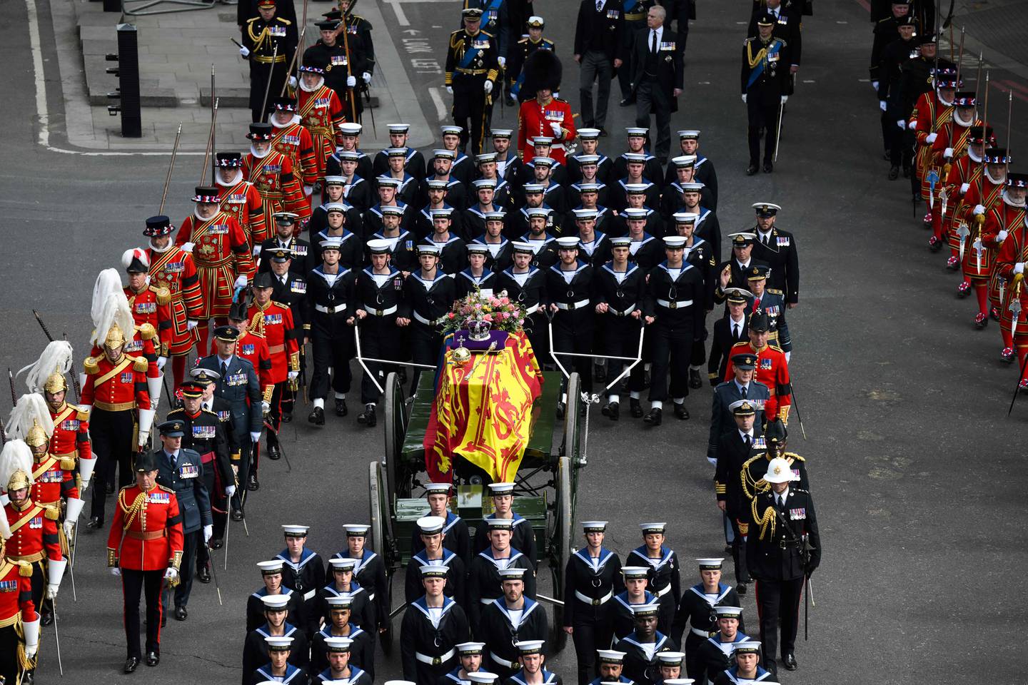 Royal Navy sailors walk ahead and behind the coffin of Queen Elizabeth II as it travels on the state gun carriage. AFP
