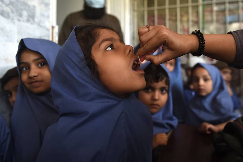 A health worker administers polio vaccine drops to a young girl at a school during a door-to-door vaccination campaign in Karachi. AFP