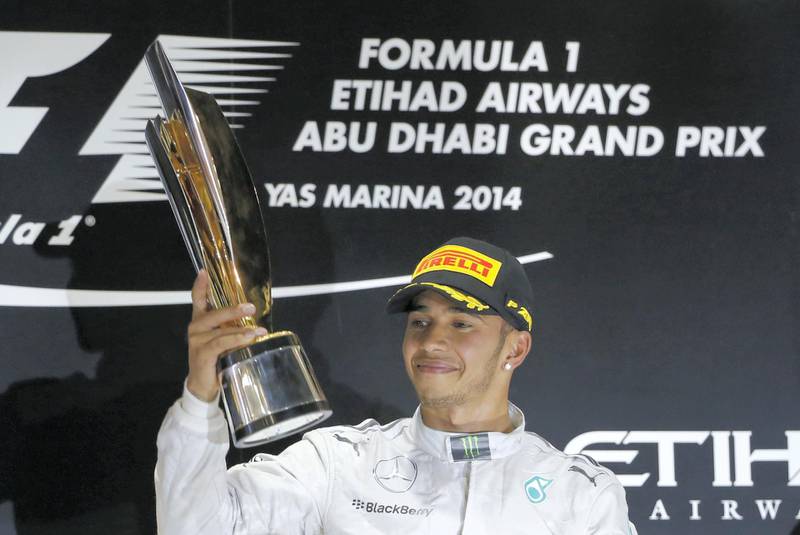 Mercedes-AMG's British driver  Lewis Hamilton celebrates on the podium at the Yas Marina circuit in Abu Dhabi on November 23, 2014 after the Abu Dhabi Formula One Grand Prix.     AFP PHOTO / KARIM SAHIB (Photo by KARIM SAHIB / AFP)