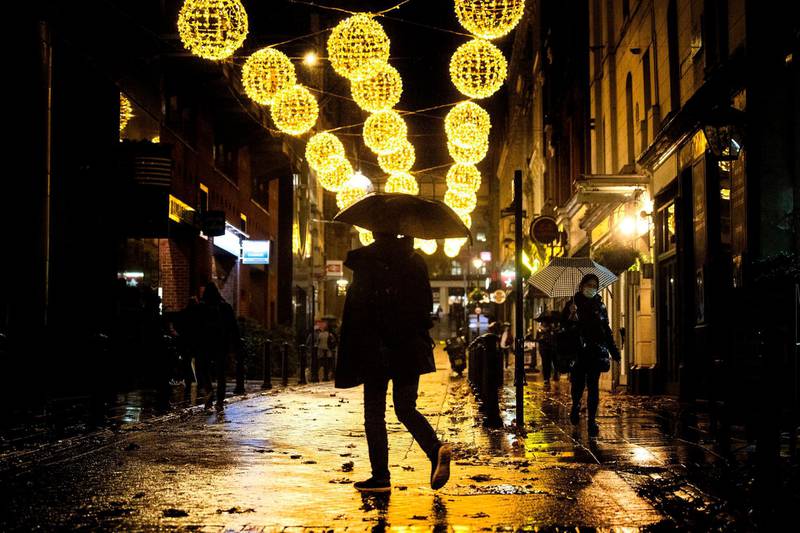A man crosses a quiet street filled with Christmas lights in central London. AP Photo
