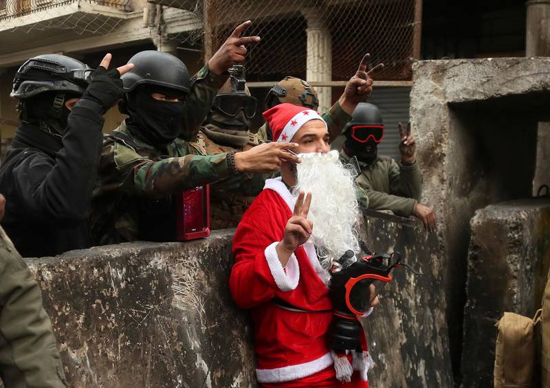 Iraqi security forces take pictures with a protester dressed as Santa Claus during ongoing protests on Rasheed Street in Baghdad. AP Photo
