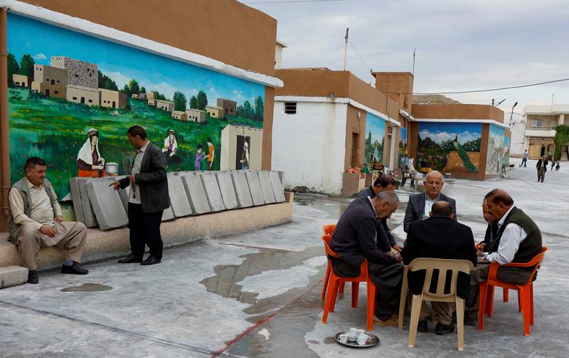 Mosul residents relax next to murals painted on houses by artist Fares Shamou Bibani. Reuters