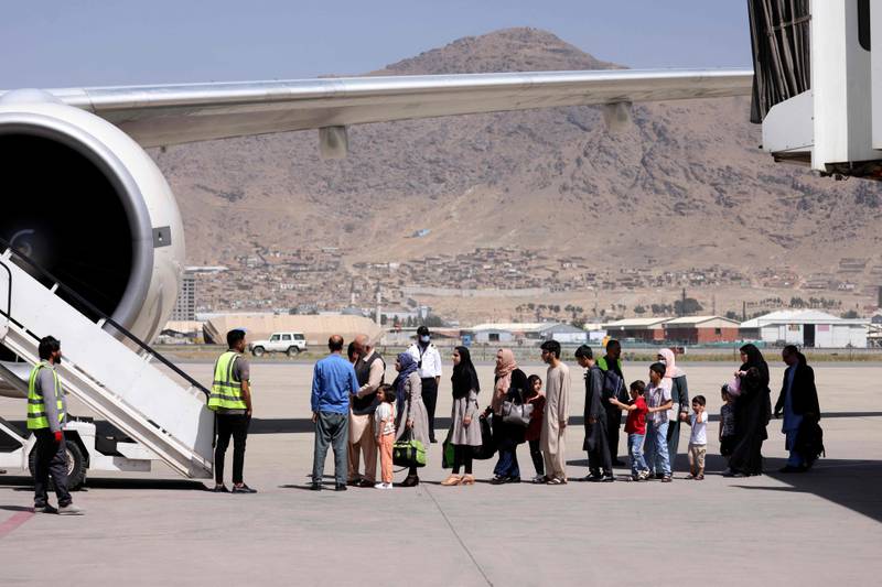 Passengers stand in a queue to board a flight out of the airport in Kabul. AFP