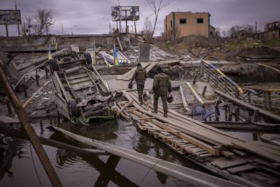 Ukrainian soldiers walk on a destroyed bridge in Irpin, on the outskirts of Kyiv. AP