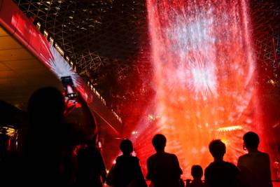 Members of the public are silhouetted against a light show projected on the Rain Vortex inside Jewel Changi in Singapore.  EPA