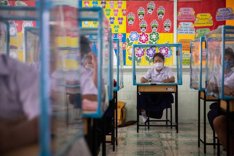 Thai students wear face masks and sit at desks with plastic screens used for social distancing at the Wat Khlong Toey School in Bangkok, Thailand. Getty Images