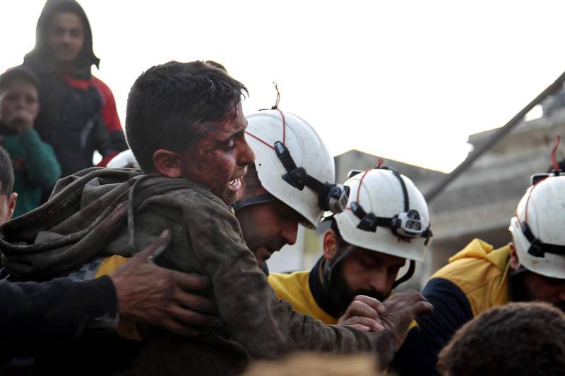 Members of the Syrian Civil Defence, also known as the White Helmets, recover a wounded boy from the rubble of a building. AFP