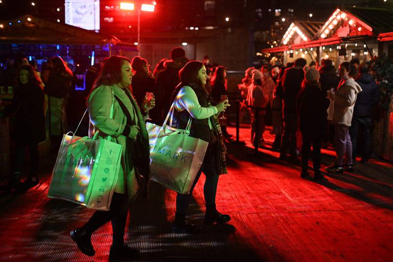 People enjoy refreshments at a Christmas market in Piccadilly Gardens in Manchester. The UK government has faced pressure to tighten coronavirus restrictions. AFP
