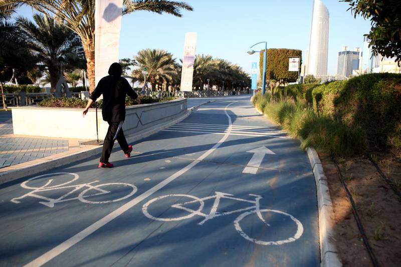A woman walks along a cycling track on the Corniche in Abu Dhabi. Authorities called on cyclists to adhere to public safety regulations.