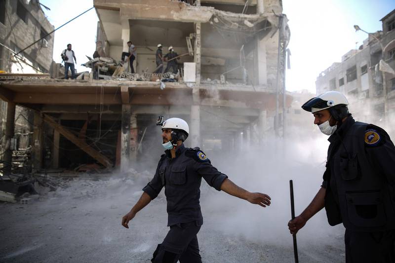 Syrian civil defence volunteers, known as the White Helmets, work around destroyed buildings following reported air strikes on the rebel-held town of Douma. AFP, file