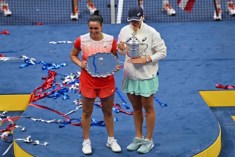 Iga Swiatek and Ons Jabeur pose for photos during the trophy ceremony following their US Open final match. AFP