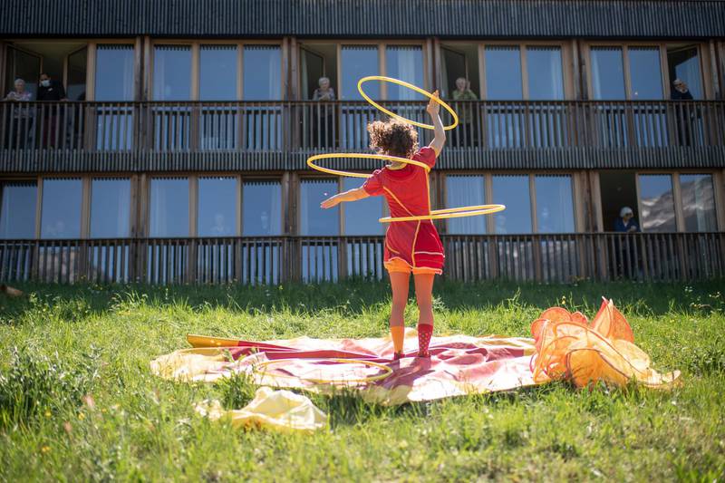 A circus performer in action, watched from doorways and surrounding windows in front of a home for the aged citizens, during the Swiss state of emergency due to the Covid-19 coronavirus, April 22, Filzbach, Switzerland. Gian Ehrenzeller/ AP
