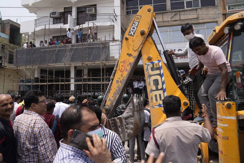 Residents and officials crowd around a bulldozer during a demolition drive in a mainly Muslim district of New Delhi, in May. Human Rights Watch has said the demolitions follow a pattern of punishment witnessed across several states against members of the minority community.   AP
