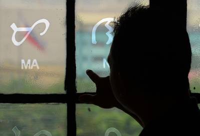 This photo taken on July 15, 2019 shows National Museum researcher Leo Batoon  pointing to a Baybayin character etched on a glass window at the National Museum in Manila.  From tattoos, shirts, and artworks to a computer font and mobile apps, Baybayin found a rebirth among millennials and professionals learning its 17 characters beyond the marginal mention in history class.