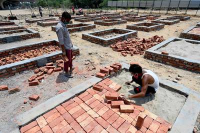 Labourers work to build cremation platforms at an empty field to extend a cremation site due to the increasing number of death for the Covid-19 coronavirus in New Delhi on May 5, 2021. / AFP / Money SHARMA
