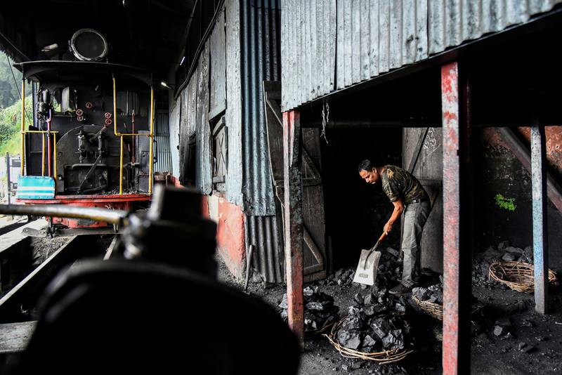 A worker breaks coal for a steam engine belonging to Darjeeling Himalayan Railway at a station in Darjeeling.