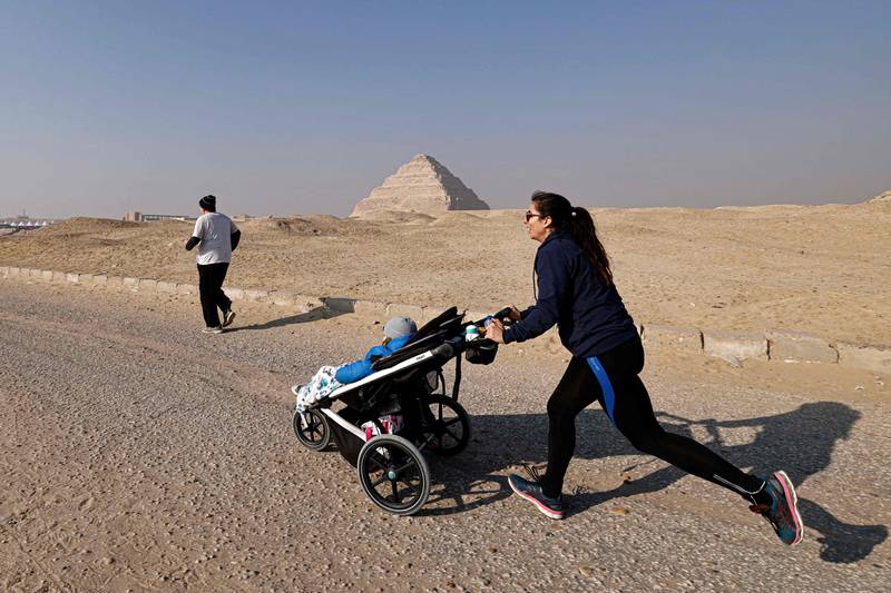A runner pushes a stroller as she takes part in race. AFP