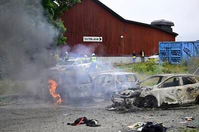 Police stand near burnt-out cars after riots at an Eritrean cultural festival in Stockholm on Thursday. AP