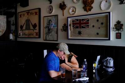 A couple embrace while talking about the passing of Queen Elizabeth at Ye Olde King's Head. AP
