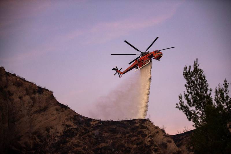 A fire department helicopter drops liquid to extinguish the Tick Fire in a neighborhood near Santa Clarita. EPA