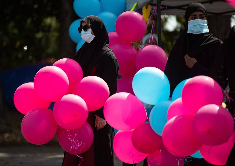 Bushra Fazal, left, 20, and her sister Hafsa Fazal, 18, wear protective face masks due to Covid-19 while holding balloons for children, during a drive-thru Eid celebration at the BC Muslim Association Richmond Jamea Mosque, in Richmond, British Columbia, Canada. The Canadian Press via AP