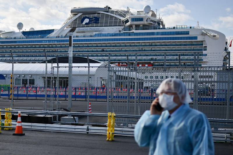 A man in protective gear speaks on the phone near the Diamond Princess cruise ship in quarantine due to fears of the new COVID-19 coronavirus, at the Daikoku Pier Cruise Terminal in Yokohama.  AFP