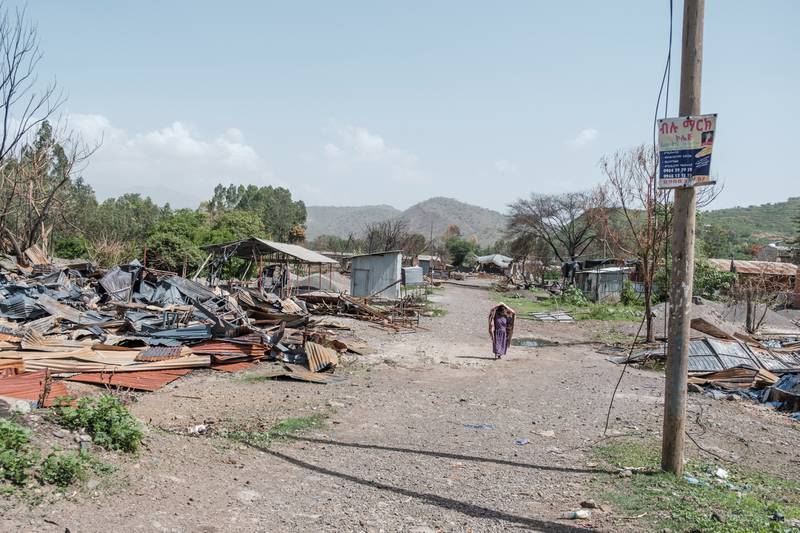 A woman walks among the remains of a destroyed factory in Ataye, Ethiopia, where more than 100 civilians died in a recent flare-up of violence.
