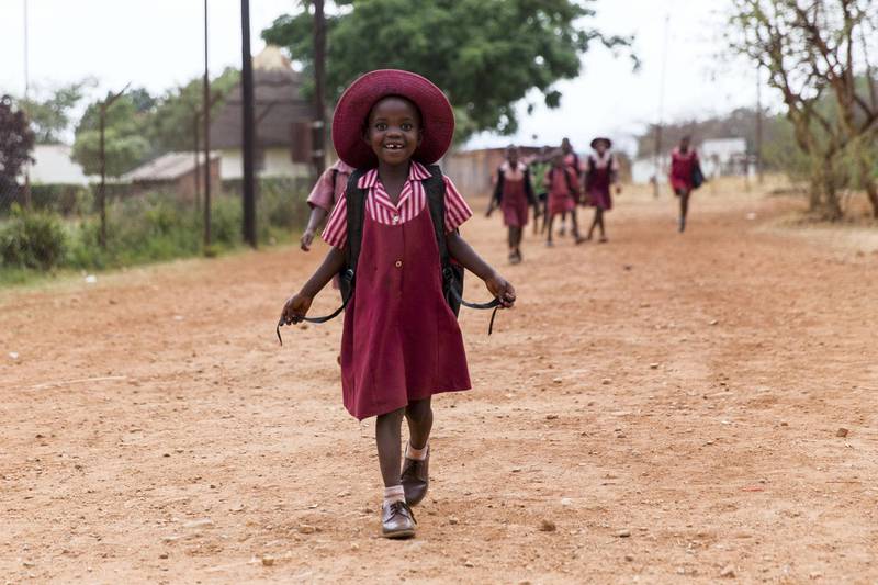 Zimbabwe, Banket - November 10, 2016: A young school girl with red school dress at the 'Sacred heart high school' in Banket is smiling to the photographer.
