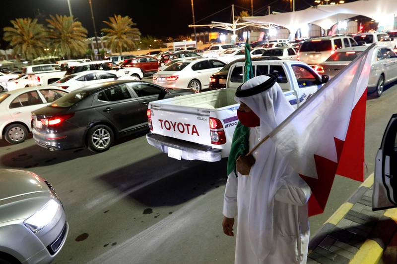 A Bahraini man holding Saudi and Bahraini national flags welcomes Saudis as they enter Bahrain via the King Fahad Causeway, after Saudi authorities lifted the travel ban on its citizens after 14 months due to coronavirus restrictions. Reuters