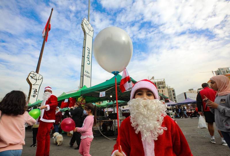 A Lebanese child dressed in a Santa Claus outfit holds a balloon at a Christmas market set up on Martyr's square, the epicentre of anti-government protests, in the capital Beirut's downtown district.   AFP