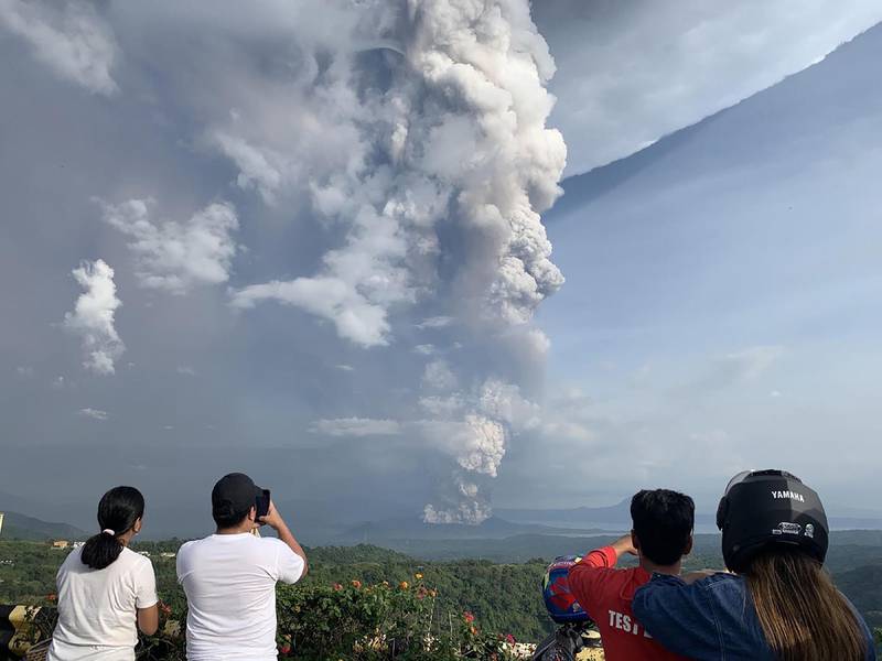 People take photos of a phreatic explosion from the Taal volcano as seen from the town of Tagaytay in Cavite province. AFP