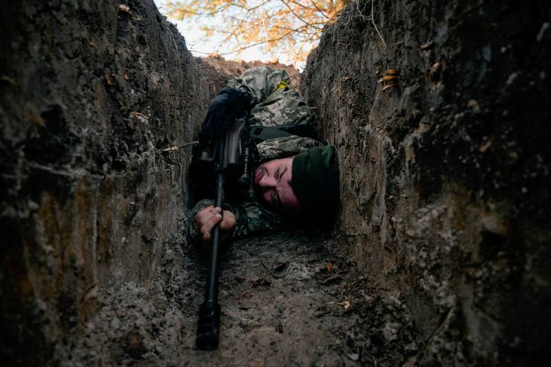 A Ukrainian soldier hides from a helicopter air strike near Demydiv, Ukraine. Reuters